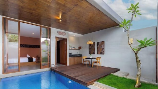Quarto de hotel moderno com uma grande janela, teto de madeira e uma pequena varanda com piscina.