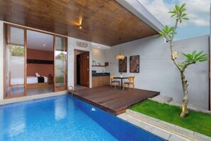 A modern hotel room with a large window, a wooden ceiling, and a small balcony with a pool.
