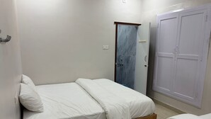 A bedroom with two single beds, a wardrobe, and a shower area. - Shree Chakra Residency (Kanchipuram)