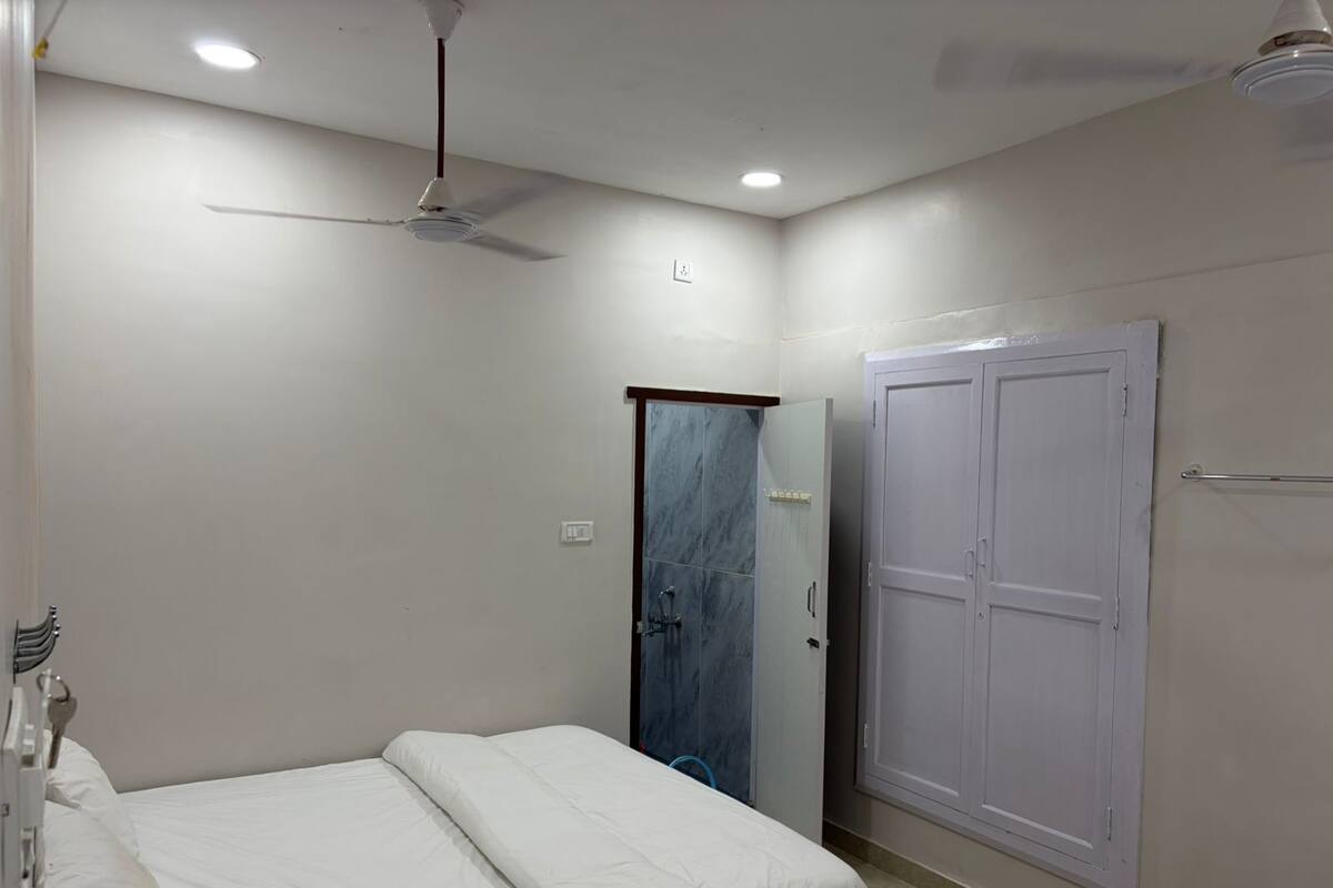 A bedroom with two beds, a wardrobe, a ceiling fan, and a door.
