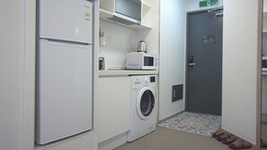 Eine kleine Küchenzeile mit Kühlschrank, Mikrowelle und Waschmaschine.