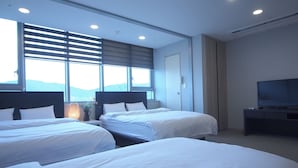 Ein Hotelzimmer mit zwei Betten, einem Fernseher und einem Fenster mit Jalousien.