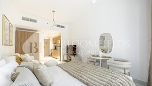 A modern bedroom with a large bed, a bedside table, a chair, and a mirror. - Bloomfeilds Central STU  OASIS Masdar (Abu Dhabi)