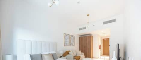 A modern hotel room with a large bed, a sitting area, and a dining table.