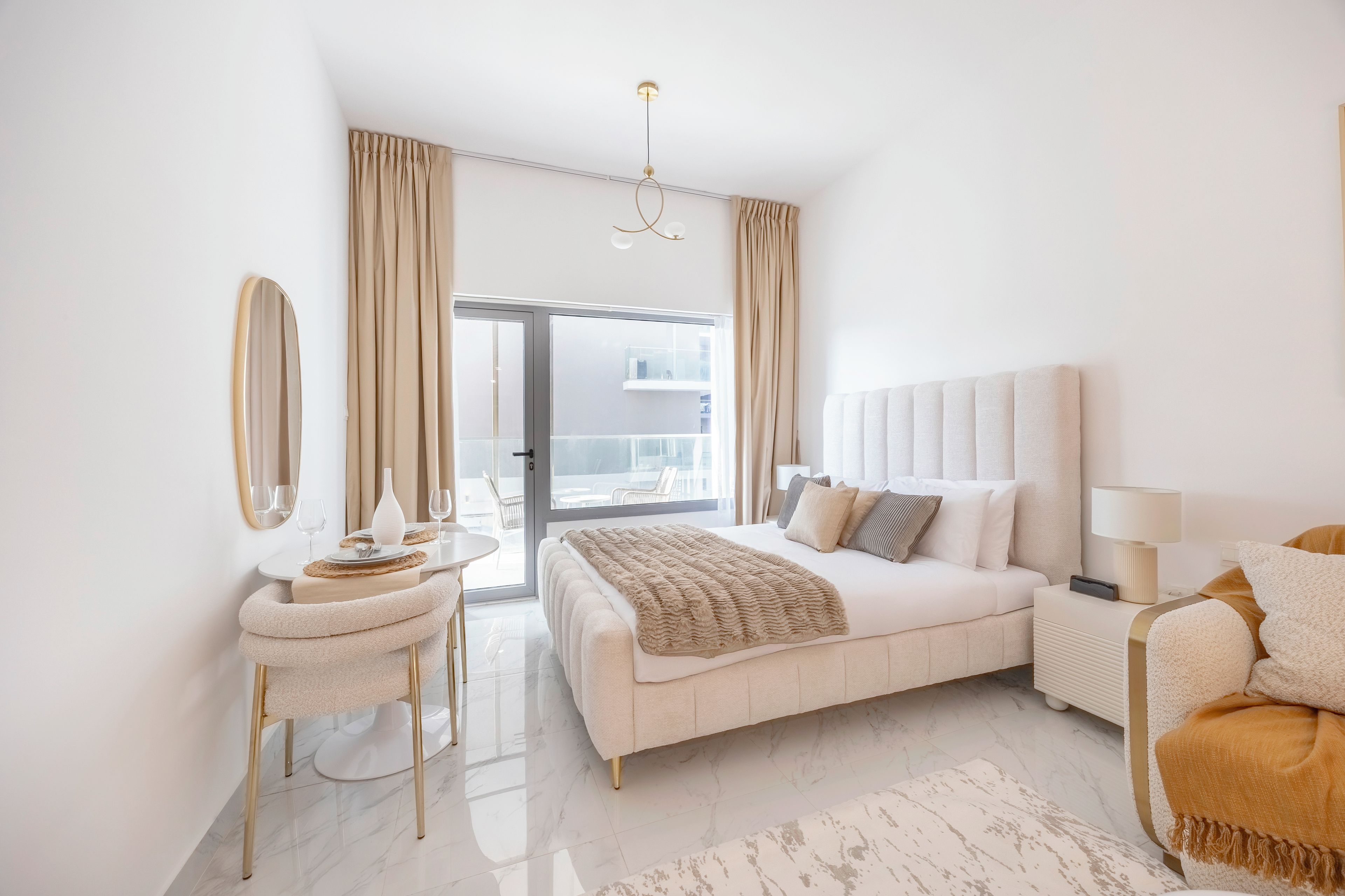 A modern bedroom with a large bed, bedside tables, a mirror, and a view of the outdoors.