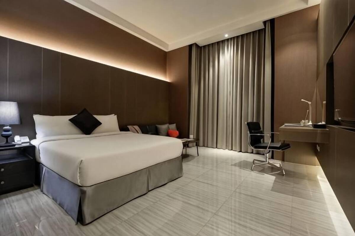 Une chambre d’hôtel moderne, dotée d’un grand lit, de tables de chevet, d’un bureau et d’une télévision.