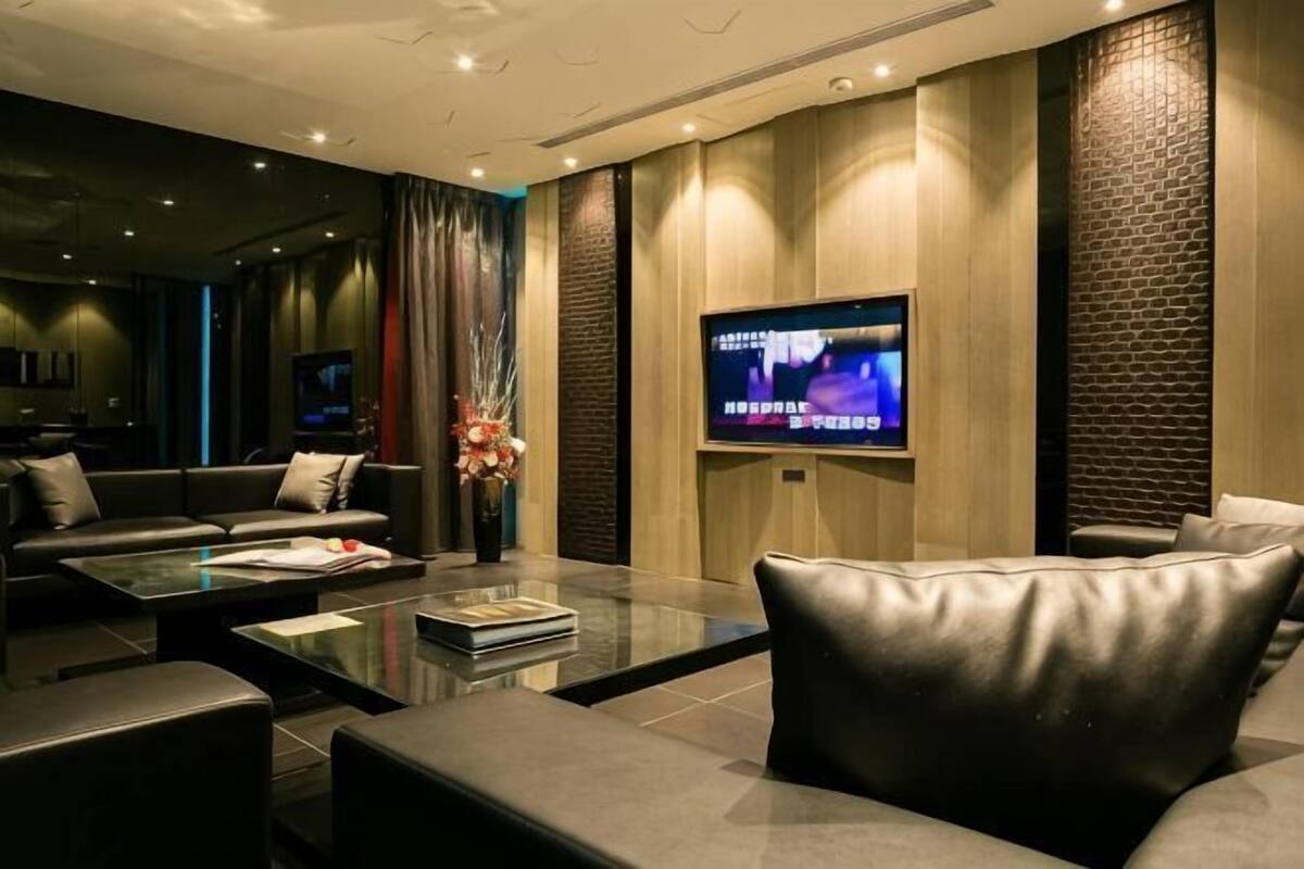 Un salon moderne avec un téléviseur à écran plat, des canapés en cuir, une table basse en verre et un vase décoratif.