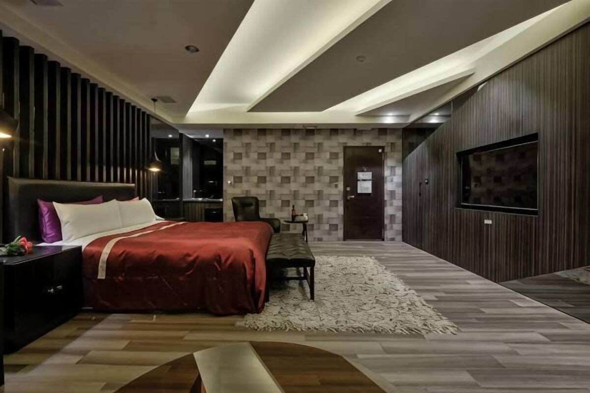 Une chambre moderne avec un grand lit, un téléviseur fixé au mur et un plancher en bois.