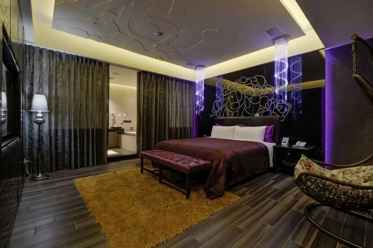 Une chambre d’hôtel moderne dotée d’un grand lit, d’un coin salon, d’une coiffeuse et d’une salle de bain.