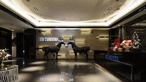A modern hotel lobby with a reflective floor, a reception desk, and a large 'MHOTEL' sign. - Tsaotun Boutique Hotel (Nantou)