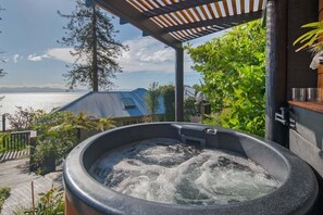 Uma banheira de hidromassagem com vista para o mar e montanhas.