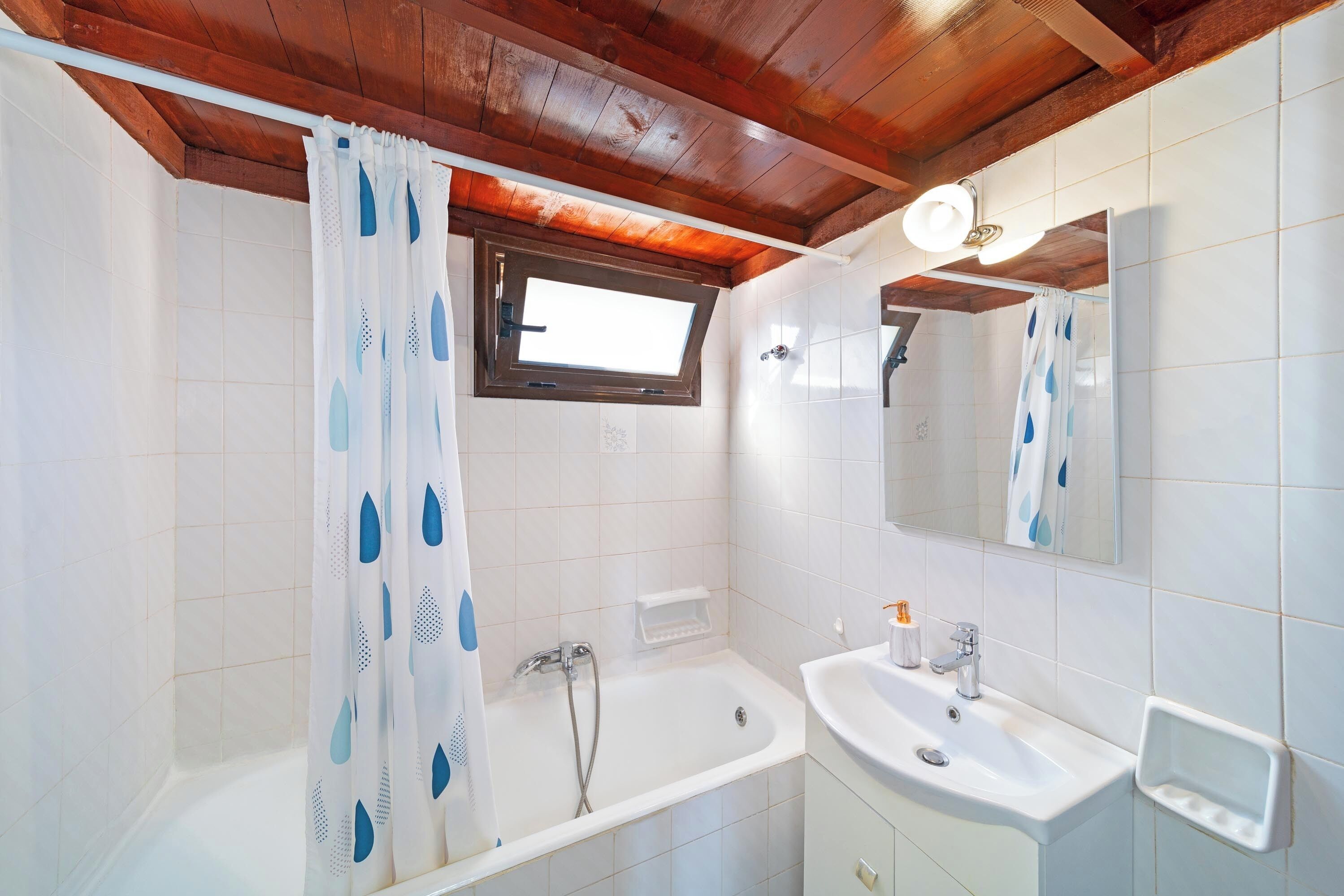 Une salle de bain avec une baignoire, un lavabo, un miroir et une fenêtre.