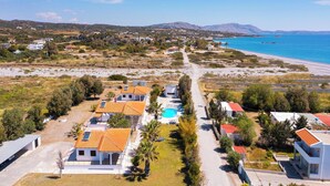 Zona residencial costera con casas, una piscina y una playa.