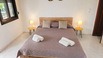 A bed with a wooden headboard, two bedside lamps, and two decorative wall pieces.
