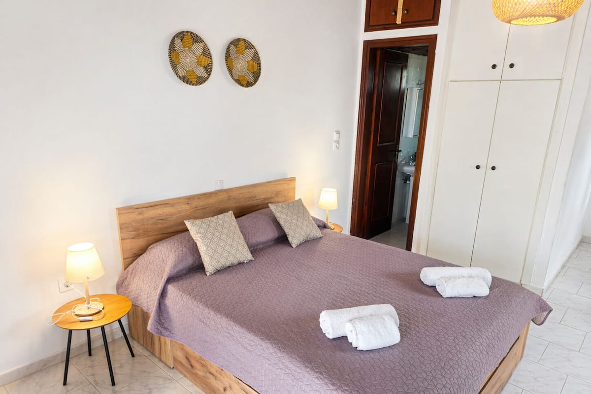 A bedroom with a wooden bed frame, two bedside lamps, a mirror, and a wardrobe.
