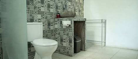 Un baño con inodoro, lavabo y cubo de basura.