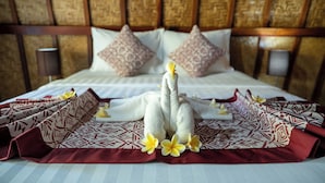 Ein Bett mit Handtüchern in Schwanenform, Kissen und einer gemusterten Bettdecke.