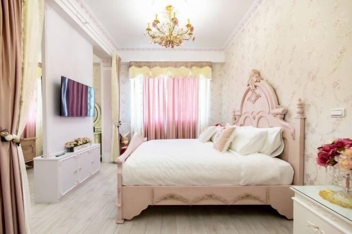 A bedroom with a bed, a dresser, a mirror, and a chandelier.