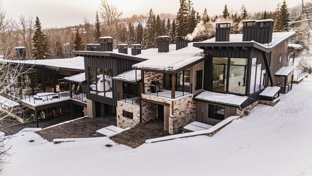 A modern multi-story house with a stone facade, large windows, and a covered outdoor area. - Ski Out on Whitefish Mountain 3BD 4BA Sleeps 14+ Unbeatable SKI Location (Whitefish)