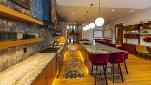 A modern kitchen with a central island, red bar stools, and a patterned rug. - Ski Out on Whitefish Mountain 3BD 4BA Sleeps 14+ Unbeatable SKI Location (Whitefish)