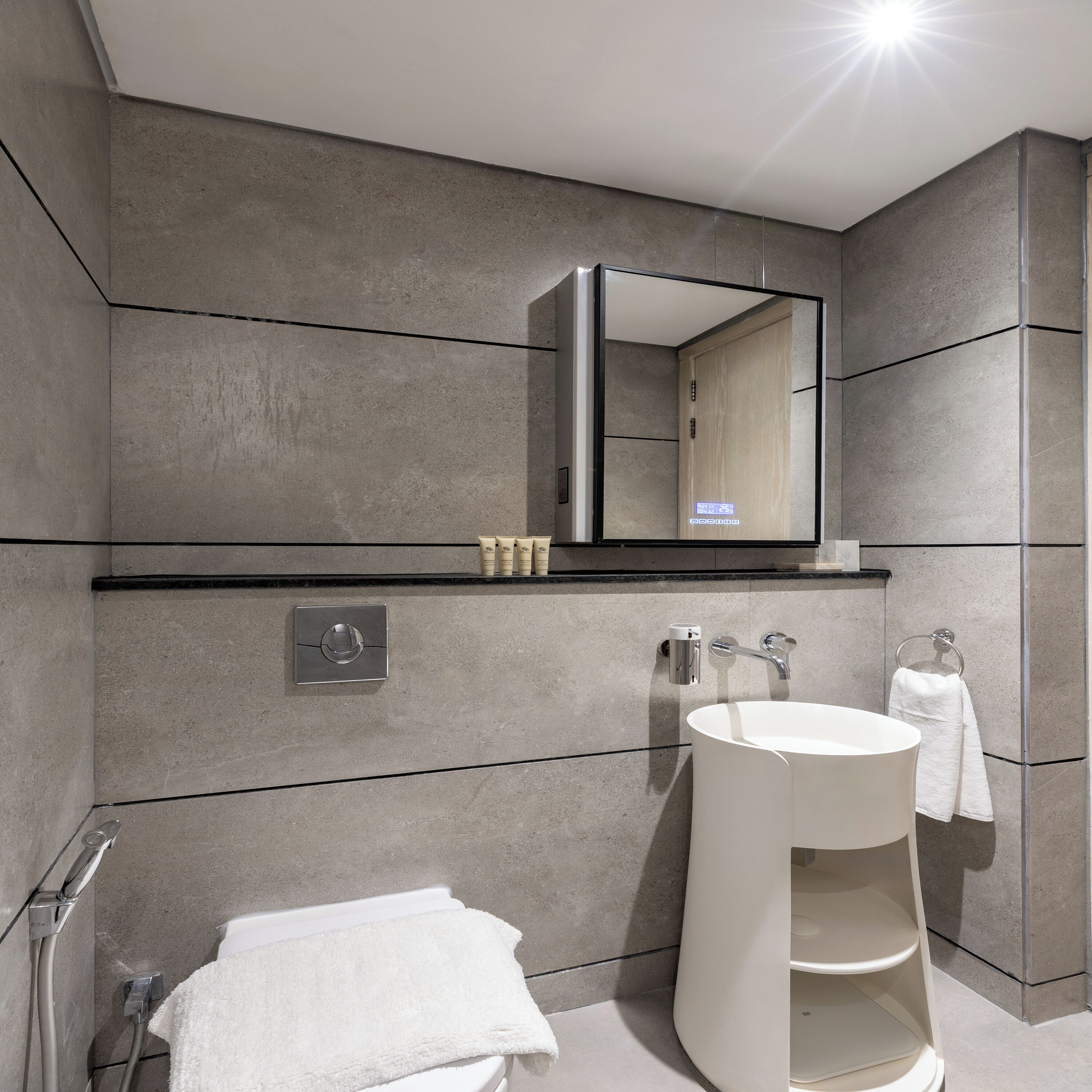 Une salle de bain moderne avec un grand miroir, un lavabo blanc et un porte-serviettes.