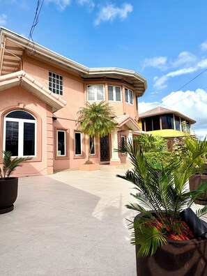 A large, two-story house with a curved roofline, multiple windows, and a paved driveway.