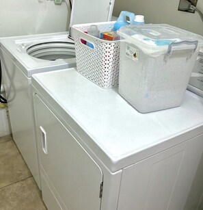 A front-loading washing machine with a basket and detergent container on top.