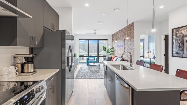 Een moderne keuken met een groot eiland, roestvrijstalen apparatuur en uitzicht op een balkon.