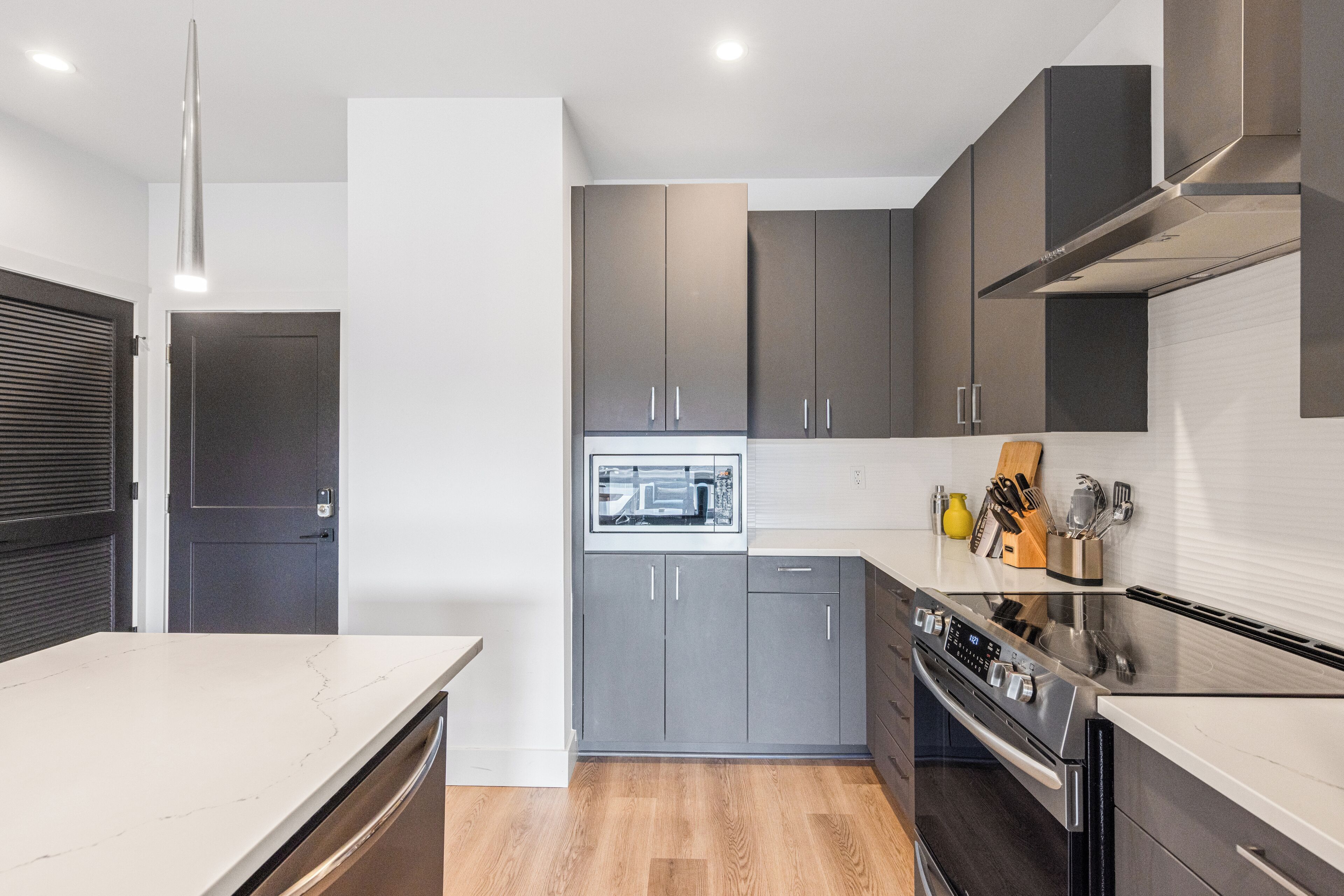 A modern kitchen with grey cabinets, a built-in oven, and a microwave.