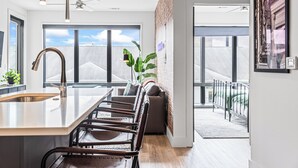 Een moderne keuken met een groot eiland, barstoelen en uitzicht op de stad.