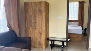 Une chambre d’hôtel moderne avec un canapé, une armoire en bois, une table en verre et un lit doté de rideaux.