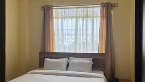 Une chambre à coucher avec un lit, des rideaux, une fenêtre et une table de chevet.
