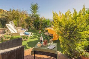 Um pátio com mobiliário de exterior, uma mesa posta para refeição e diversas plantas.