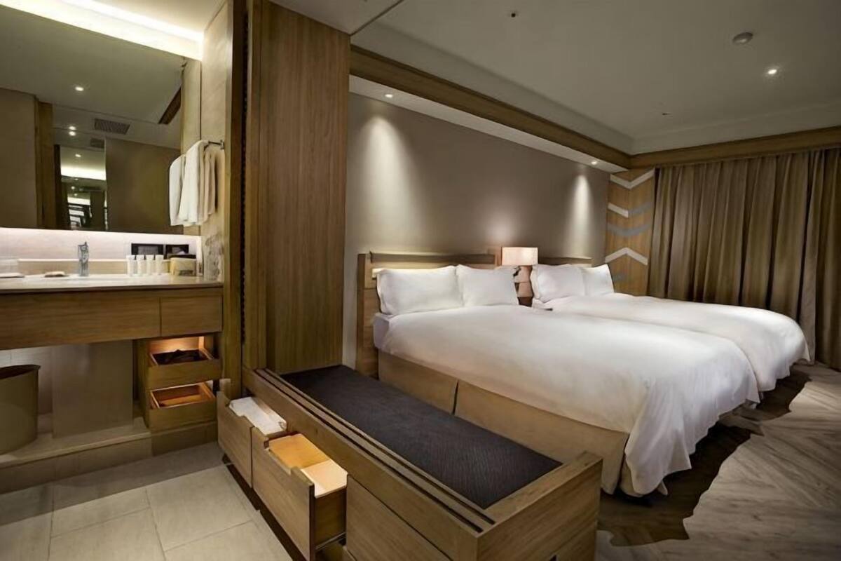 Une chambre d’hôtel avec un grand lit, une coiffeuse en bois, un miroir et une table de chevet.