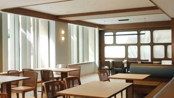 A restaurant interior with tables and chairs, large windows, and a modern design.