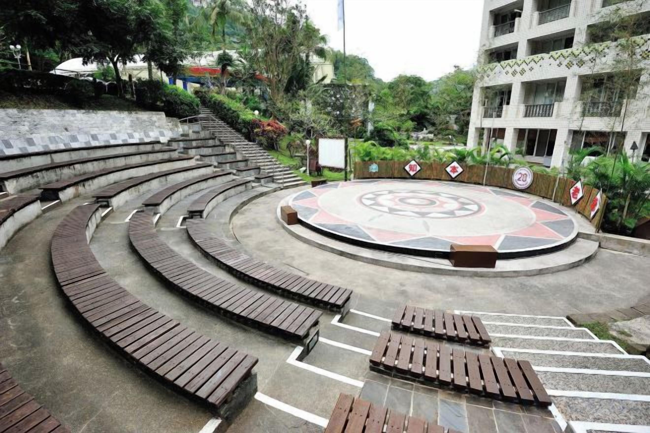 A circular outdoor seating area with benches and a central decorative element.