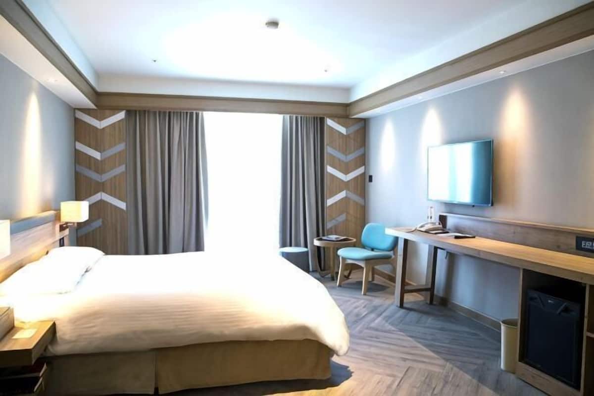 Ein Hotelzimmer mit Bett, Schreibtisch, Sessel, Fernseher und Kamin.