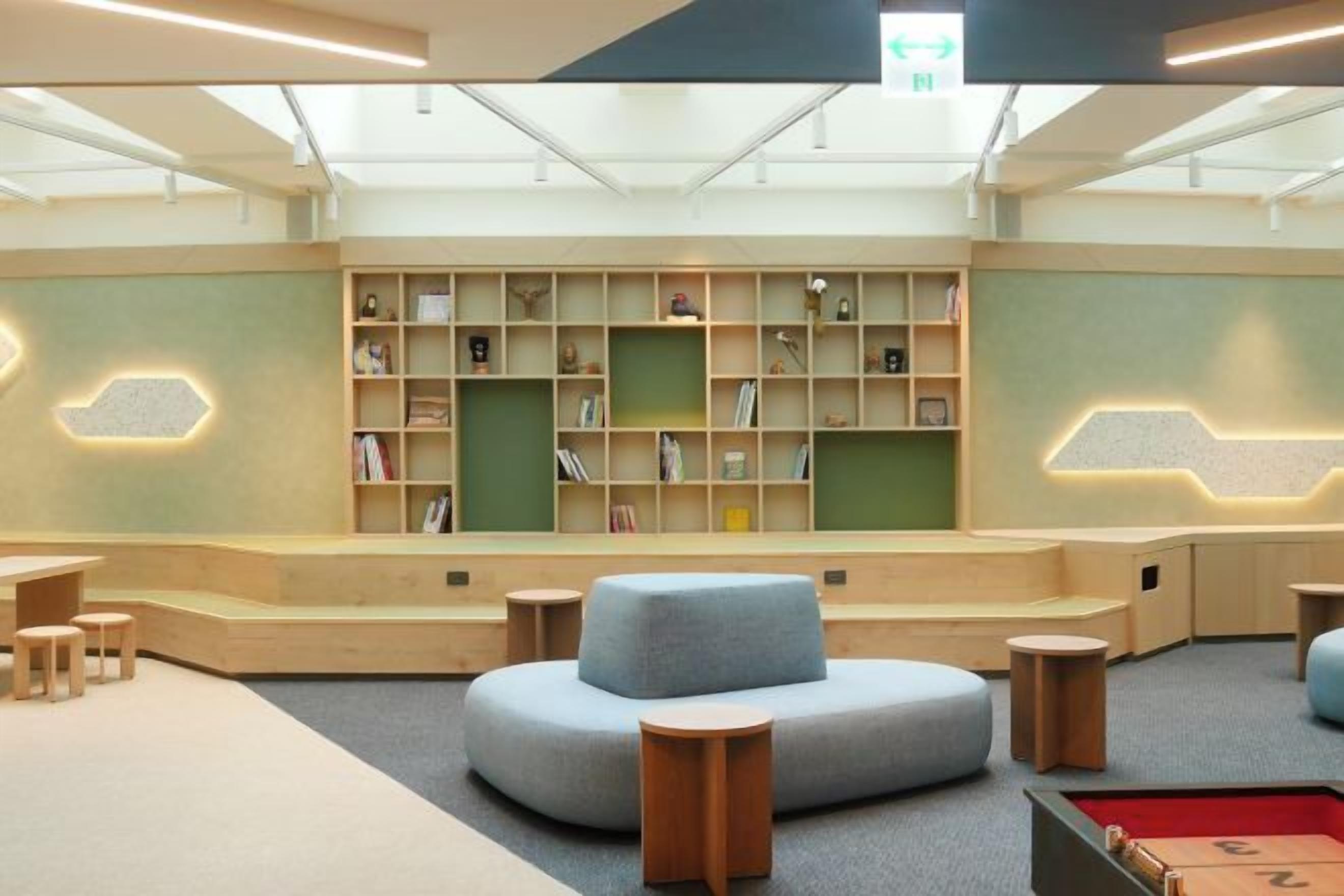 A children's library with bookshelves, seating areas, and a pool table.