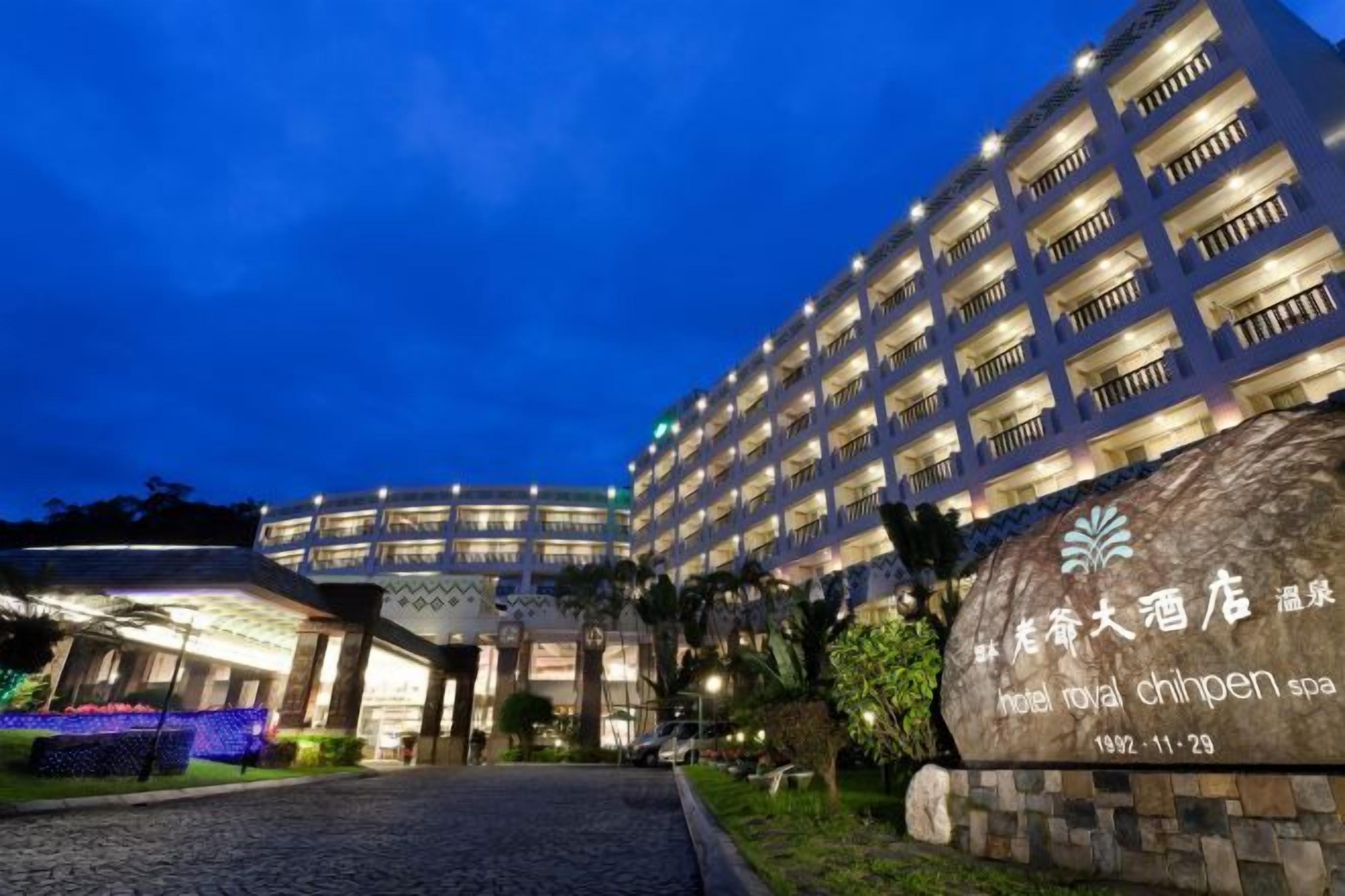 Un hotel de varios pisos, un cartel grande con caracteres chinos y una zona de entrada bien iluminada.