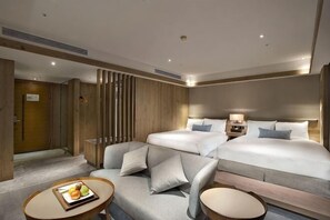 A hotel room with a double bed, a sofa, a small table with fruit, and a decorative wall panel. - Hotel Royal Chihpen Spa (Taitung)