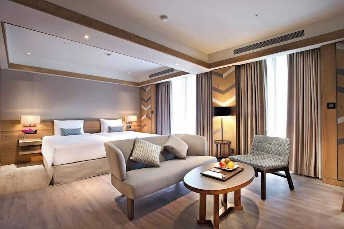 Ein Hotelzimmer mit Bett, Sofa, Sessel, rundem Tisch und Lampe.