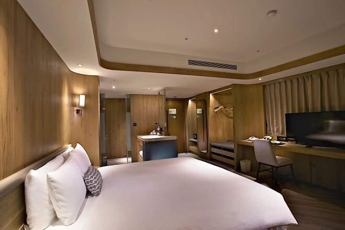 Ein Hotelzimmer mit einem großen Bett, einem Schreibtisch, einem Fernseher und einem Badezimmer.