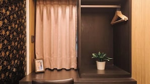 A room with a dark wooden desk, a hanging wooden hanger, a potted plant, and a framed photo on the desk. - Welove meworld Inn (Taipei)