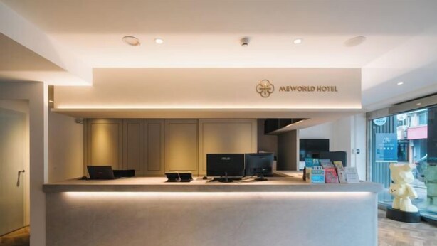 A hotel reception desk with a modern design, featuring a flat surface, a logo, and multiple computer monitors. - Welove meworld Inn (Taipei)