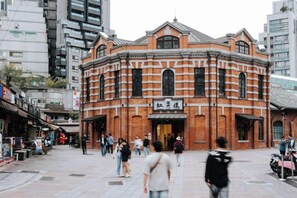 A historic building with a brick facade and arched windows, located in a busy urban area with pedestrians and shops. - Welove meworld Inn (Taipei)