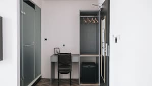 A compact room with a desk, chair, wardrobe, and a hanging coat rack. - Welove meworld Inn (Taipei)