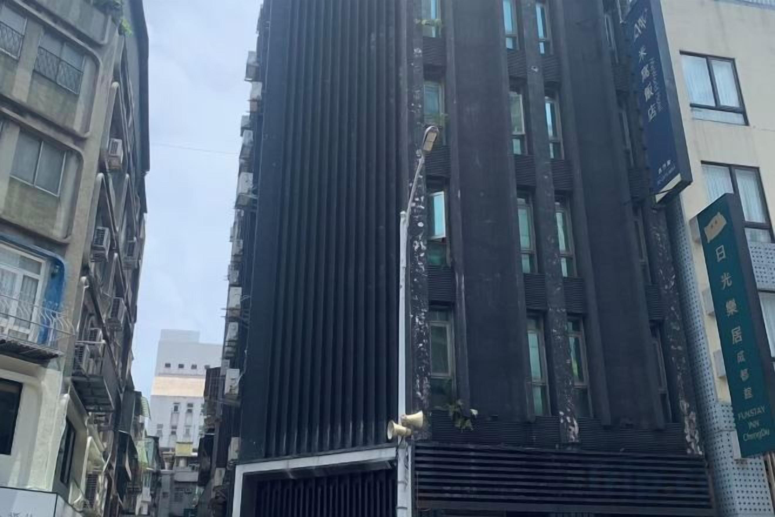 A tall building with a modern design, featuring a prominent vertical structure and a series of windows.