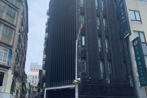 A tall building with a modern design, featuring a prominent vertical structure and a series of windows.