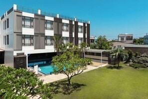 A modern multi-story building with a swimming pool, surrounded by a well-maintained lawn and some trees. - Shan Ban Bay By Riverinn (Pingtung)