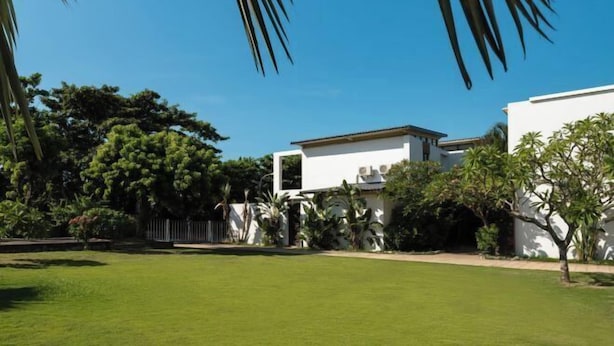 Een modern huis met een verzorgd gazon en tropische planten.
